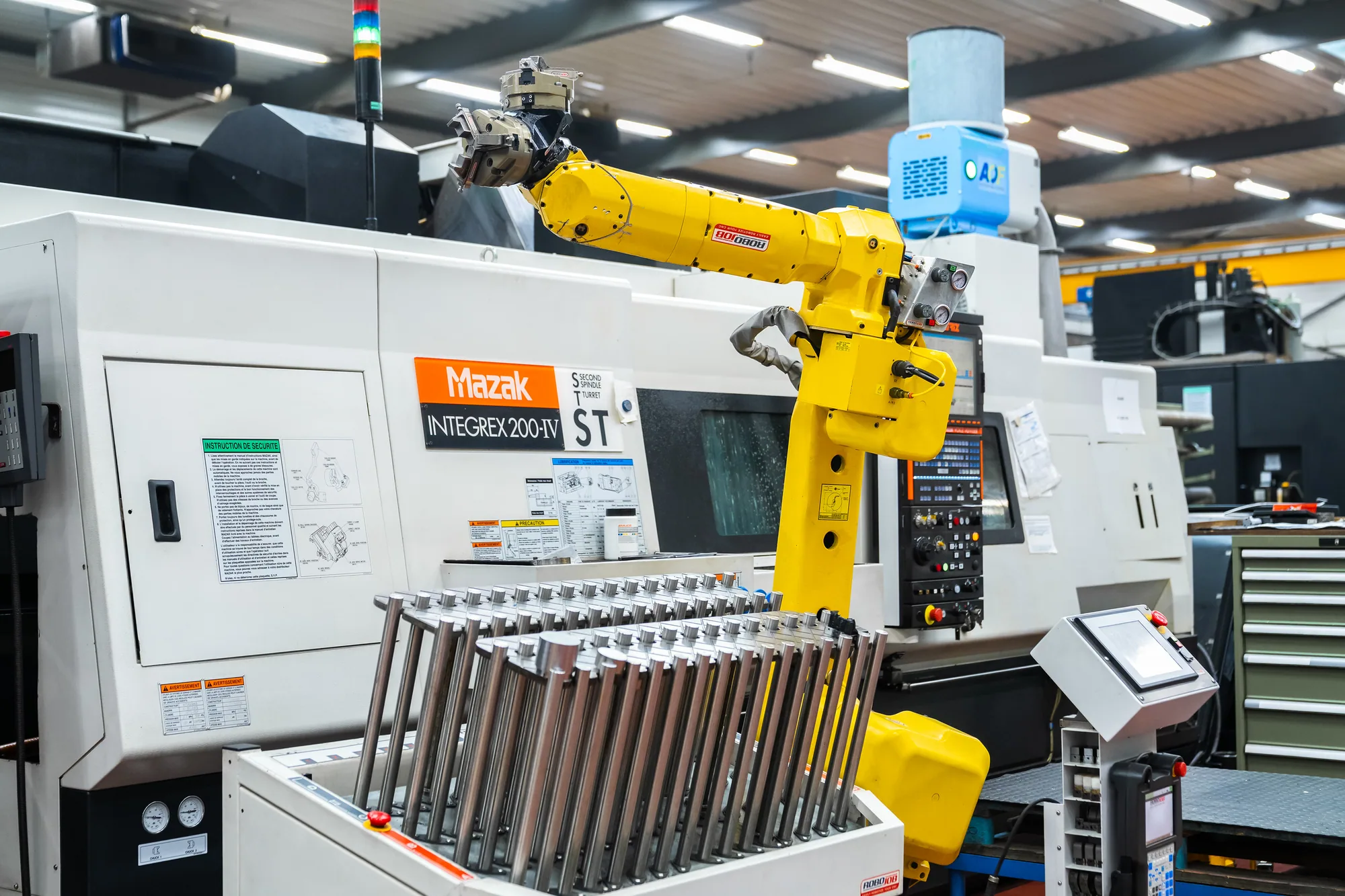 Draai-freescentrum met een gele beladingsrobot en een rek met werkstukken